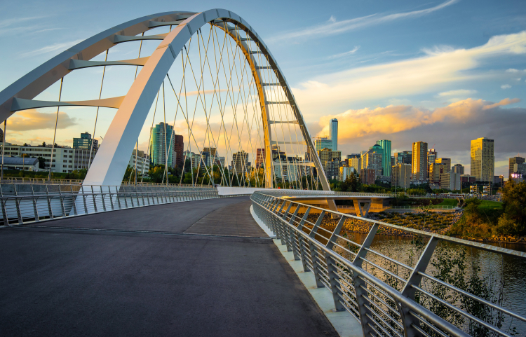A white-arched bridge spans over a body of water, framed by a vast city in the background