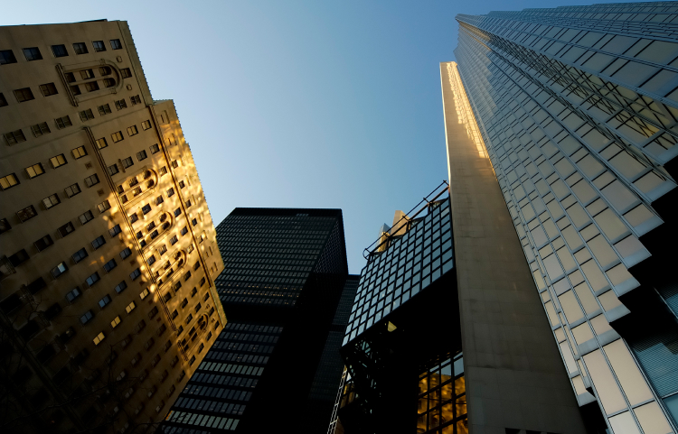 A collection of high-rise buildings viewed from below with sun casting unique reflected light on their façade